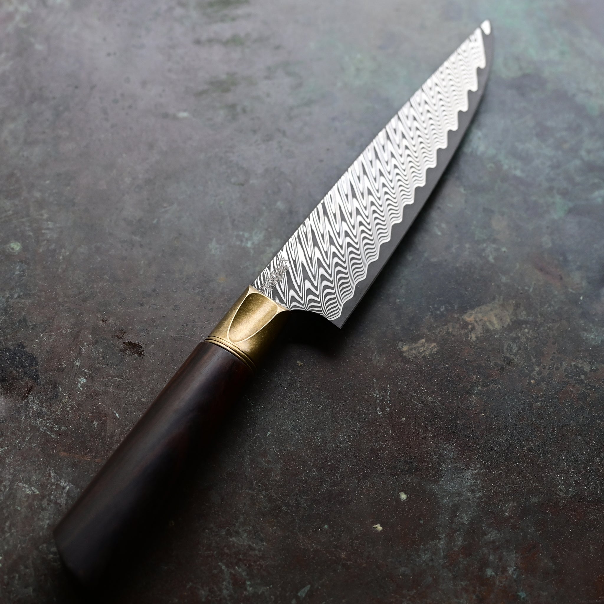 A one-of-a-kind 6.5" Meridian petty knife with a sawtooth Damascus blade, natural bronze bolster, and a straight-grained Turkish walnut handle in rich brown tones, hand-forged by John Phillips