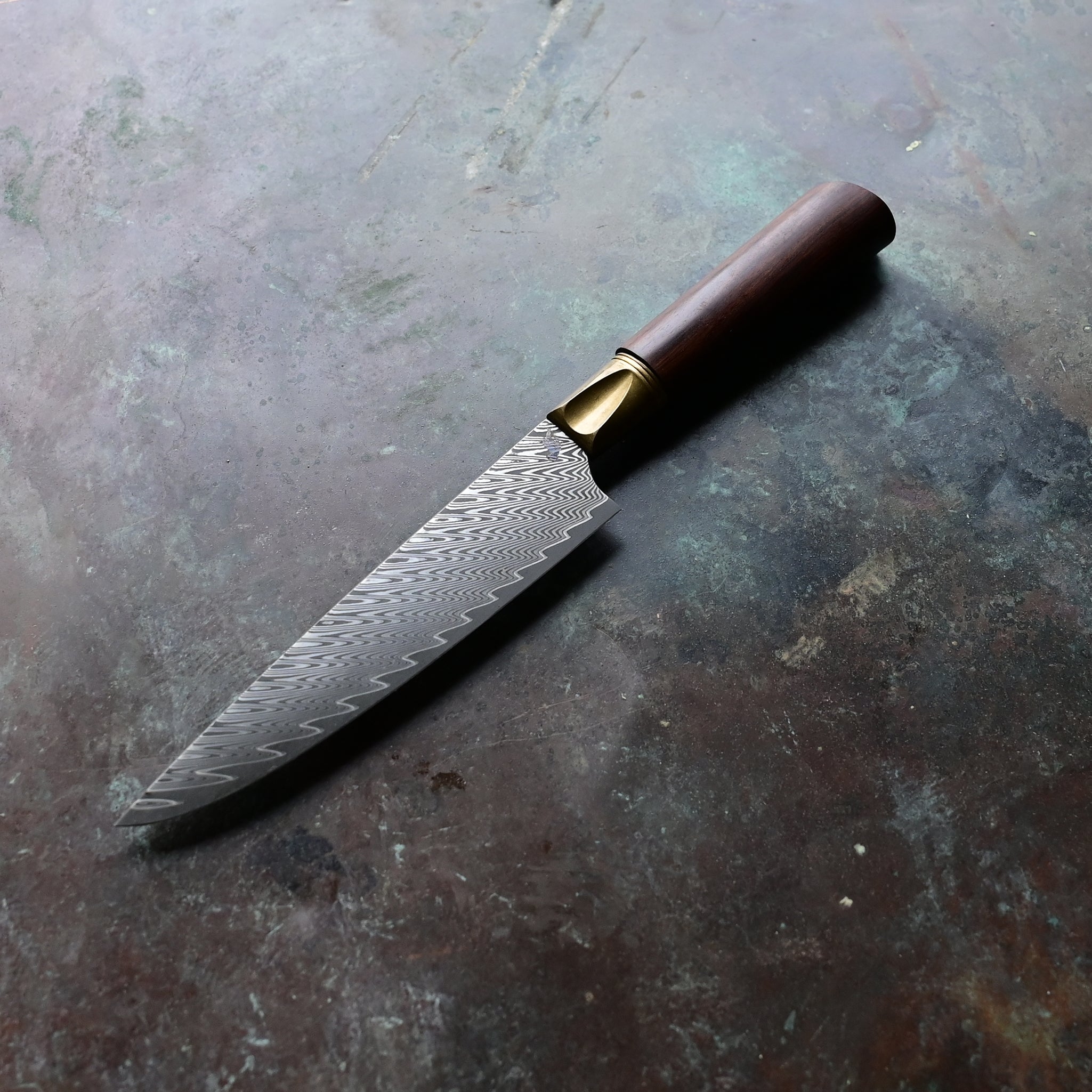 A one-of-a-kind 6.5" Meridian petty knife with a sawtooth Damascus blade, natural bronze bolster, and a straight-grained Turkish walnut handle in rich brown tones, hand-forged by John Phillips
