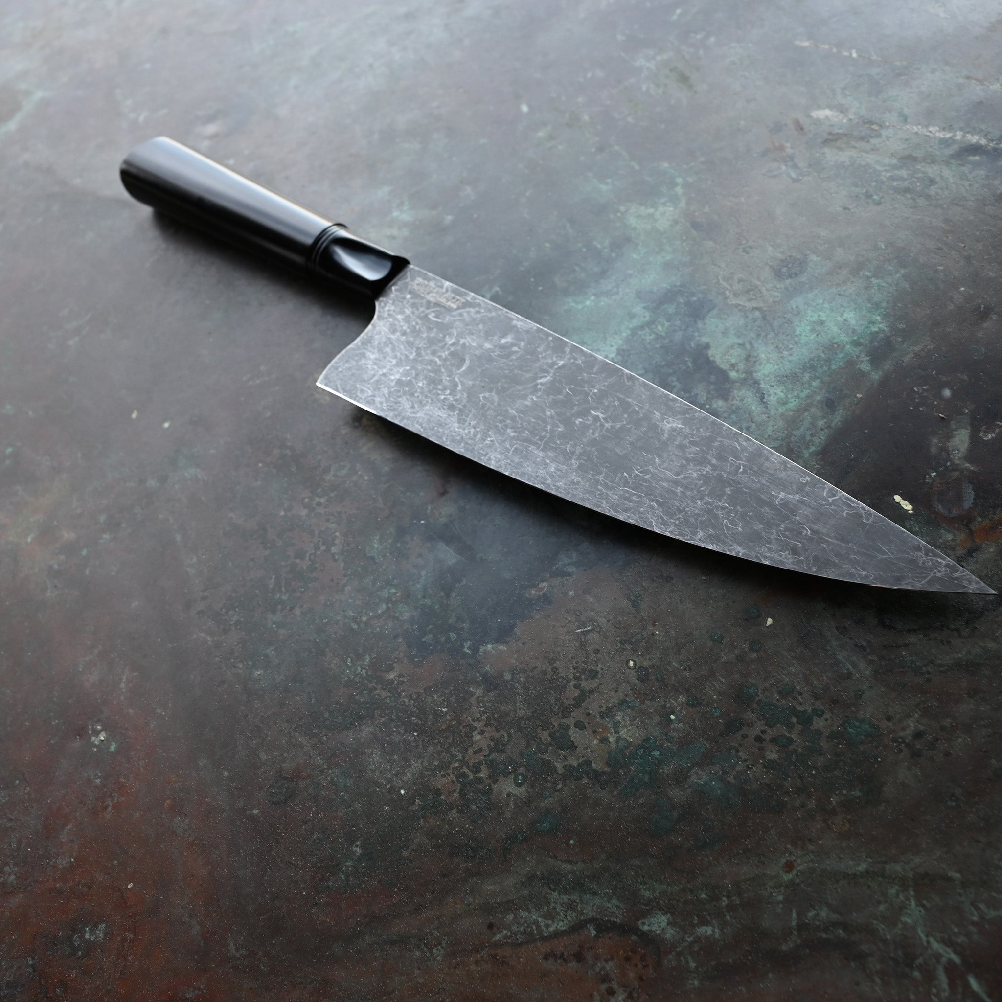 CHEF KNIFE ON CONCRETE BACKGROUND ANODIZED ALUMINUM BLACK HANDLE AND BOLSTER