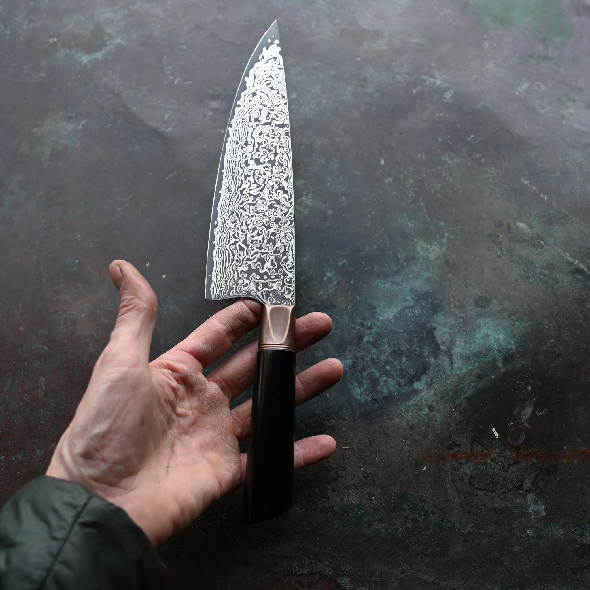 Damascus Steel Chef Knife with Antique Bolster and Black Handle on Concrete Background