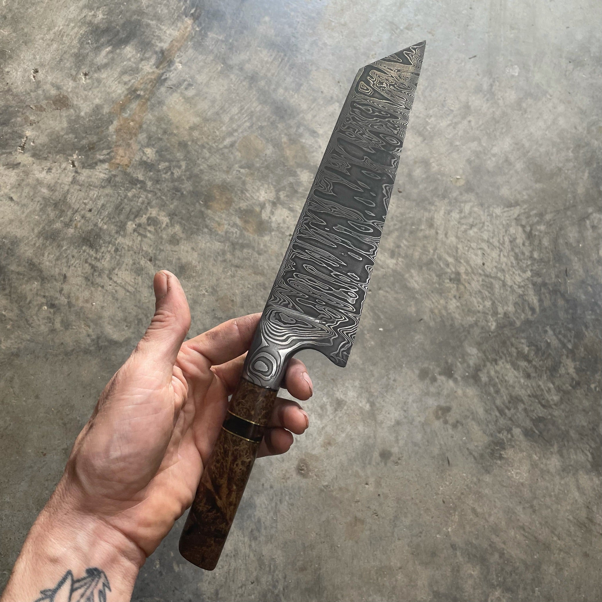 integral bolster knife being held by hand on concrete background
