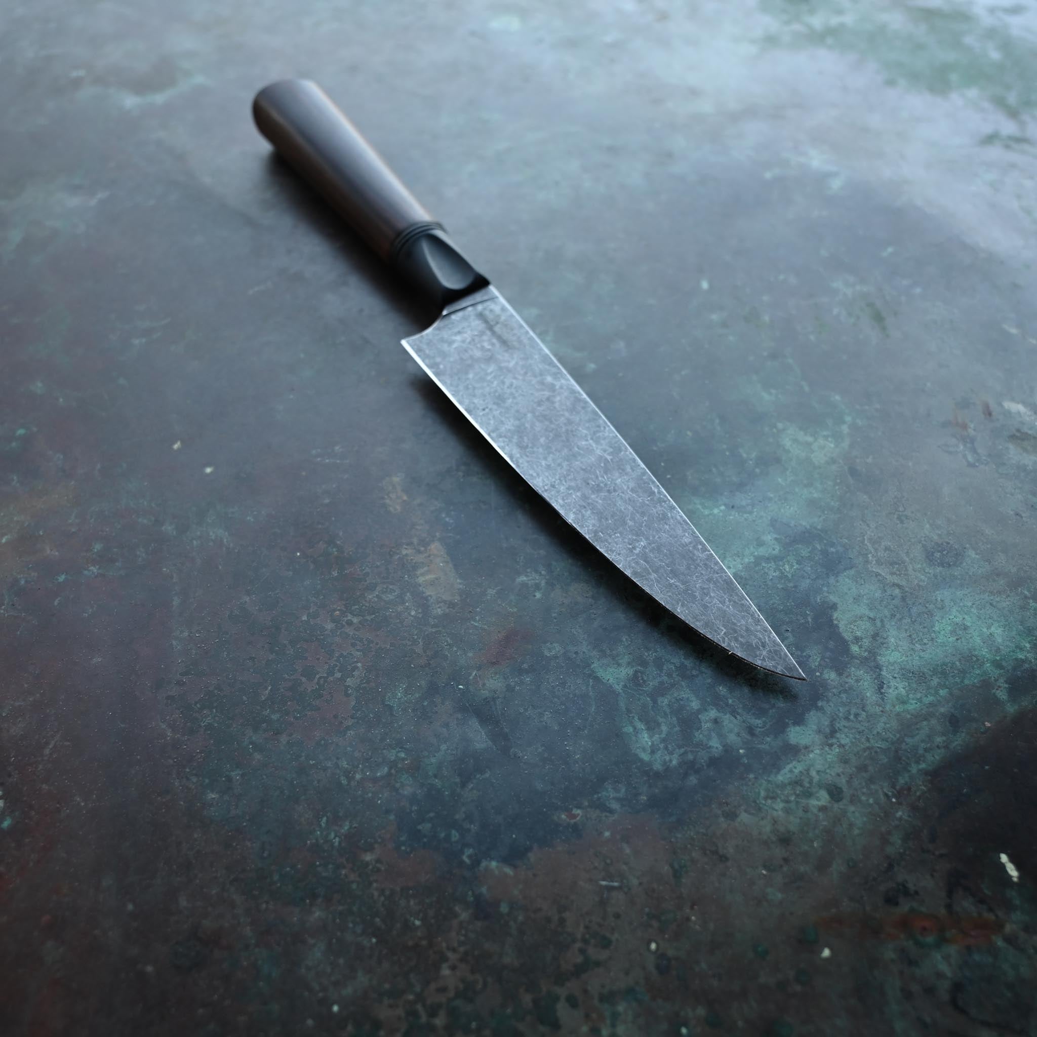 PETTY KNIFE WITH CLARO WALNUT WOOD HANDLE ON A CONCRETE BACKGROUND