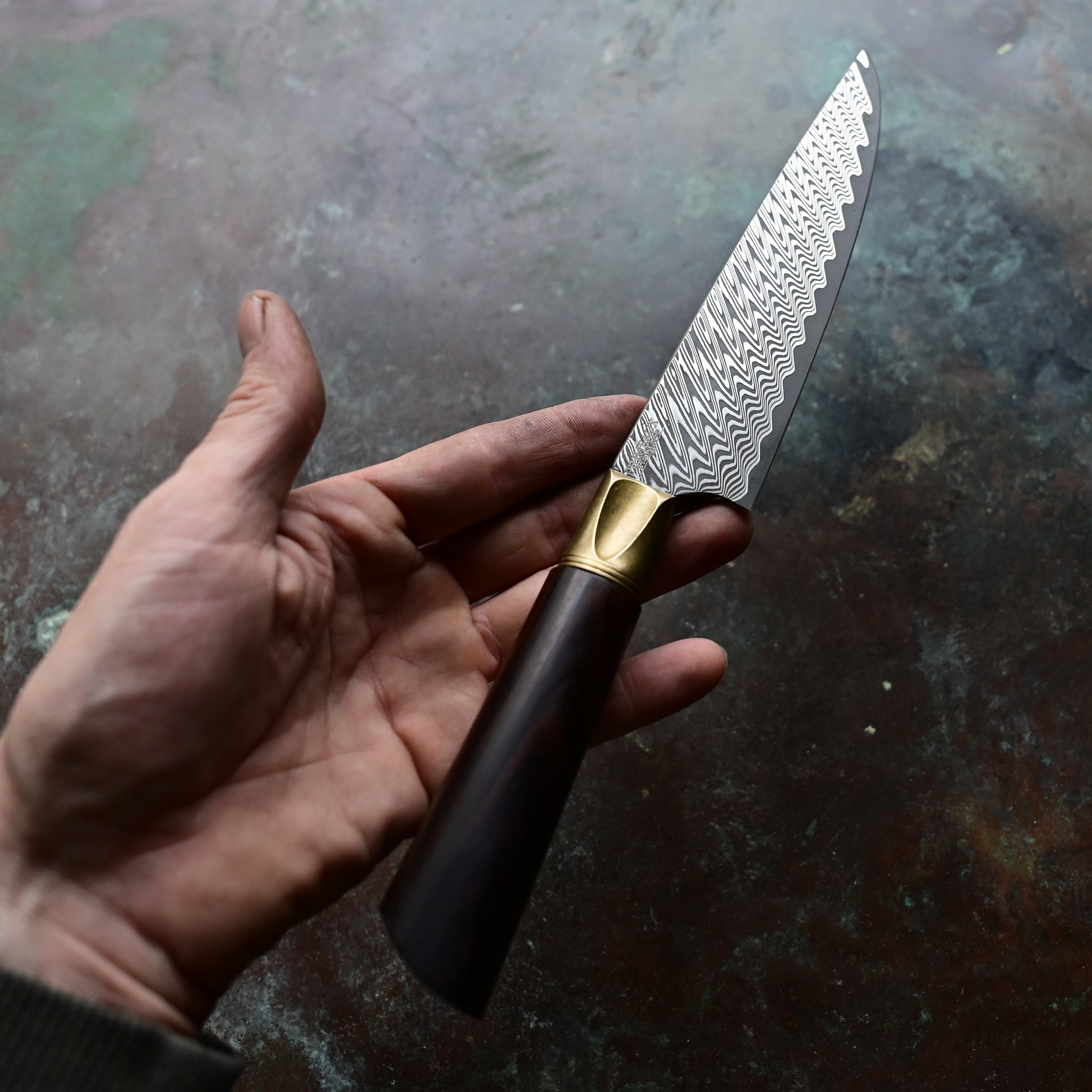 A one-of-a-kind 6.5" Meridian petty knife with a sawtooth Damascus blade, natural bronze bolster, and a straight-grained Turkish walnut handle in rich brown tones, hand-forged by John Phillips